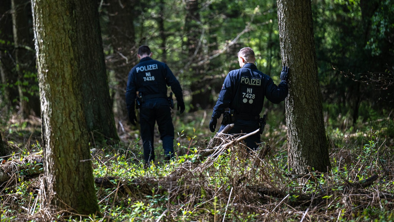 Einsatzkräfte durchsuchen ein Waldstück.