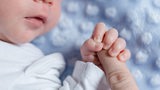 Ein Baby umfasst einen Finger (Symbolbild)